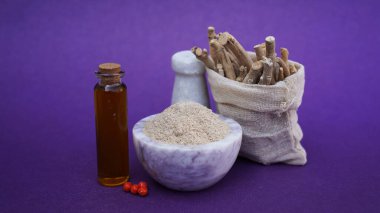 Ashwagandha Dry Root, oil and powder also known as Withania Somnifera, Ashwagandha, Indian Ginseng, Poison Gooseberry, or Winter Cherry. Isolated on Purple Background. clipart