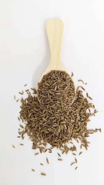 Beyaz arka planda bir kaşık kimyon tohumu