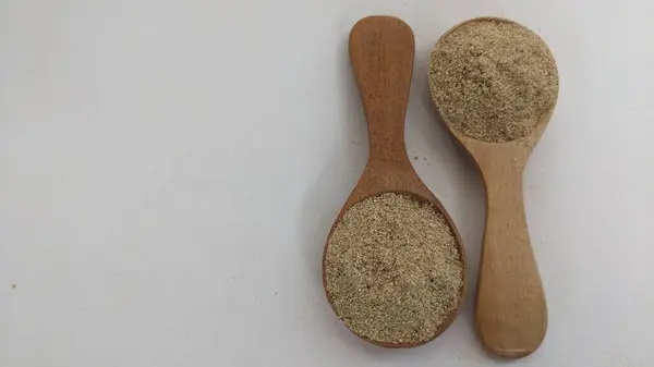 Tahta bir kaşıkta, beyaz bir kaşık üzerinde izole edilmiş.