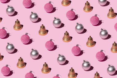 Altın ve gümüş noel mücevherleri ve pembe arka planda ziller. Noel ve yeni yıl yaratıcı desen.