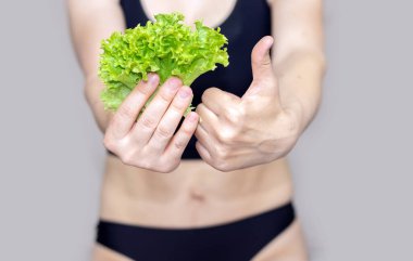 Sıska kadın salata yapraklı marul yiyor seksi doğum sonrası karın ağrısı. Kadın karnına uygun ve şişman kız için baş parmak kaldırıyor.