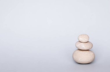 Spa sağIık kavramı. Piramit deniz tuzu ve orkide çiçeğindeki çakıl taşları gri kağıt arka planda izole edilmiş. Dalgalar gibi deniz tuzu.