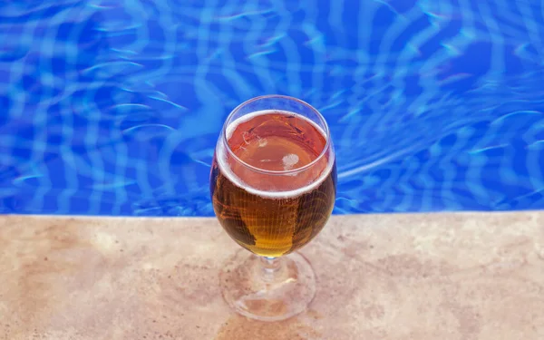 Havuz kenarında taze soğuk biralı bardak mavi renk su dalgaları metin kopyası için boş alan oluşturur. Tatil zamanı yolculuk, otel gezisi, dinlenme yeri deniz plajında dinlenme.