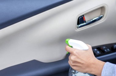 car wash and interior chemical cleaning concept.hand use microfiber cloth and spray to clean lateral door from inside,retractable rear view mirror,steering wheel.modern hybrid vehicle clean inside