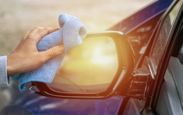 car wash and interior chemical cleaning concept.hand use microfiber cloth and spray to clean lateral door from inside,retractable rear view mirror,steering wheel.modern hybrid vehicle clean inside