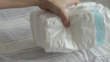 baby diapers in pack woman mother hand or bed finger counting throwing on blanket chaotic or in row arrangment.mom hand hold new diaper white no paint drawn close up 4k slow motion motherhood 