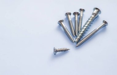 screw different sizes in a row and one is down, light blue background. Stainless bolt kid hand. Hardware repair tools isolated, free space for text, copy paste. be, think different, unique concept