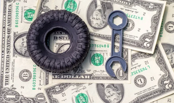 tire replacement change concept.rubber black tires from toy car and plastic wrench key isolated.dollar bills toy car wheel.safety tyres change by yourself or in auto service.how to and mistakes