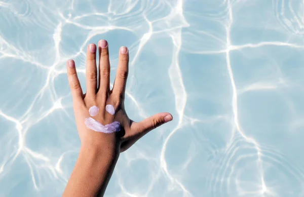 sun shape drawn from body spf uv protection cream lotion on teeneager girl or boy kid child hand shoulder against pool water.summer vacation red skin tan sun block cream