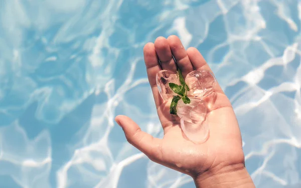 teenager girl hand holding heart shape lollipop or silicone pop it toy ice cubes ice cream against pool water slide summer time vacation sparkling waves.family fun sunshine