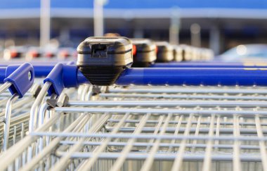 many trolley shopping cart with coin lock anti theft system outside in row sunny day different angles blue handle chain blocked carts,details.man analysis receipt prices money spent next to car