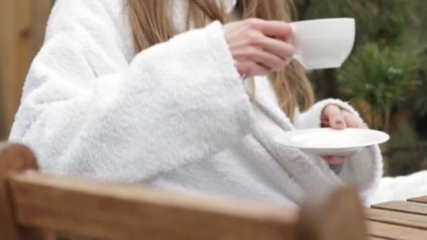 Kobieta Białym Szlafroku Zewnątrz Siedzi Krześle Pijąc Kawę Filiżanki Flip — Wideo stockowe