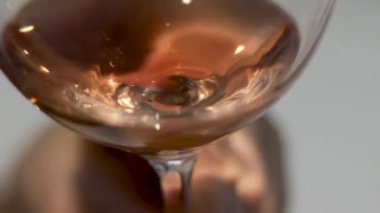 rose white wine drink room light through glass. woman playing with fingers hand palm taking glass approaching and remove from camera alcohol drink evening dinner bad illumination conditions