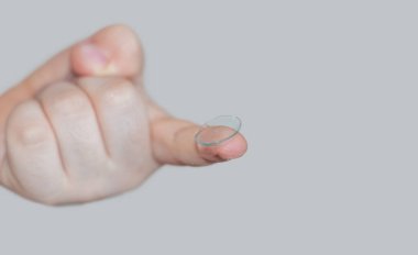 kid child little boy holding silicone contact lens on finger or trying to get out the lenses from case box.improve vision better with optical issue problem myopia.safety wearing isolated on beige back