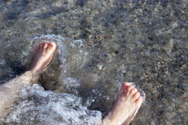 kid playing on beach sand running digging using plastic toys crab lobster seahorse shell shape rake and sprinkler.sunny summer vacation day child preschooler boy feet legs in water waves