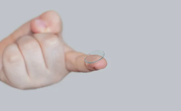 Küçük çocuk parmağında silikon lens tutuyor ya da lensleri kutusundan çıkarmaya çalışıyor. Optik sorunlu miyopya ile görüşü iyileştirmeye çalışıyor.