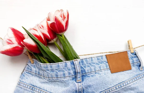 tulips on jeans and spring calling on smartphone.slide to answer incoming call.kid holding bouquet of flowers wrapped in paper on window sill.easter holiday origami rabbit mother women day march 8th