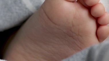 Bebek ayak parmakları battaniyenin altında şampuan banyosu jeli şişesiyle video reklamı çocuk bakımı anne kadın el masajı çocuk ayakları şirin küçük elleriyle ayak parmakları tutan bebek