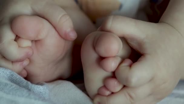 婴儿脚趾头盖在毛毯下可爱的幼儿与洗发水洗澡水瓶广告视频身体幼儿保育母亲用手按摩男孩脚趾头用可爱的小手抱住婴儿 — 图库视频影像