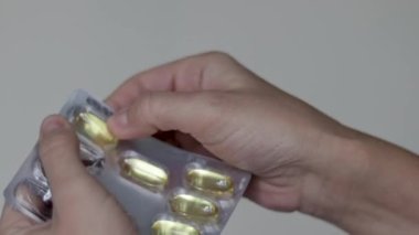 Kadın plastik kabarcıktan ya da beyaz şişe haplarından kapsül balık yağı haplarından birini alıp palmiyeye döker. Bir adet yuvarlak kalsiyum hapı. Kadınları parmaklarıyla yuvarlar. Yiyecek takviyesi vitaminleriyle oynar.