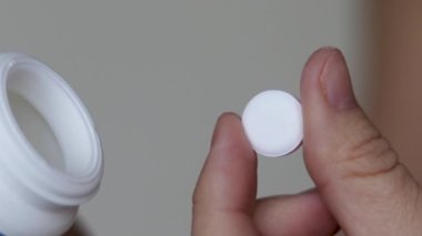 Kadın plastik kabarcıktan ya da beyaz şişe haplarından kapsül balık yağı haplarından birini alıp palmiyeye döker. Bir adet yuvarlak kalsiyum hapı. Kadınları parmaklarıyla yuvarlar. Yiyecek takviyesi vitaminleriyle oynar.