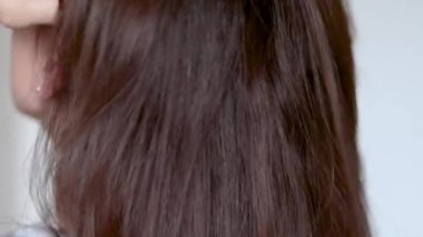 Gülümseyen genç bir kadın modern bir saç fırçası kullanıyor. Saç kurutma makinesi ve hacimsel dönüşümlü kafa yavaş çekimde. Kurutma makinesinin termal ve seramik kaplaması. Kaküllerden önce karışık saç.