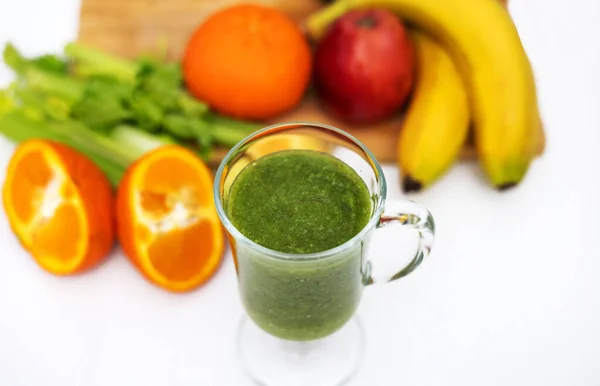 stock image healthy smoothie in glass and fruits all around on wooden board kitchen table and background.slim fit weight loss take natural vitamins.bio tangerine celery spinach kiwi and apple.mashed fruits 