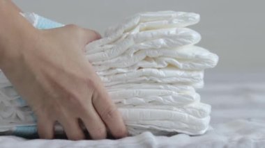 Bebek bezi istifle, kadın bebek bezi, anne eli, avuç içi ile itme, beyaz bebek bezi, yatağa yavaş çekimde bebek bakımı, yeni doğmuş bebek bakımı konsepti.