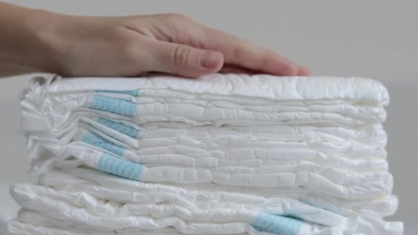 婴儿在床上堆放了许多尿布女人妈妈的手拿着一个或者用手掌按压着一个 白色的空尿布扔在床上慢动作母幼婴儿新生儿保育概念 — 图库视频影像