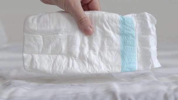 婴儿在床上堆放了许多尿布女人妈妈的手拿着一个或者用手掌按压着一个 白色的空尿布扔在床上慢动作母幼婴儿新生儿保育概念 — 图库视频影像