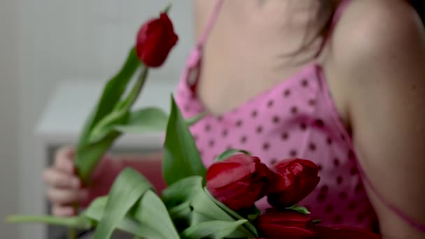チューリップの花を持つ繊細な女性笑顔愛撫手首腹腹部おなか1つの花チューリップ付き 笑顔千年紀の女性はパンツの中にメッセージを保持花束を送信します 春のイースター — ストック動画