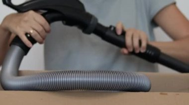 Kadın yeni elektrik süpürgesini açıyor ve gri halıyı fırçalıyor. 4 bin gerçek zamanlı ev pisliği temizleme konsepti. Karton kutulu eller, tek tek halı aletleri, toz fırçası uzatma çubuğu eklentilerini kaldırıyor.