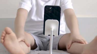 Sevimli çocuk elinde bir buket lale tutuyor, kutu hediye yatakta oturuyor, anneye hediye veriyor, 8 Mart Uluslararası Kadınlar Günü. Çocuk burnuna lale kokusu alıyor. Pantolonlu ve telefonlu laleler bahar geliyor.