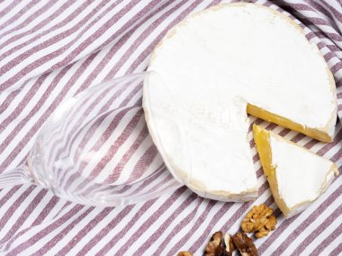 Gül şarabı şişesi, cam, yuvarlak peynir, tek dilim, ceviz, mantar ve tirbuşon karışımı mutfak çizgili havlu ya da gri arka plan taklidi.