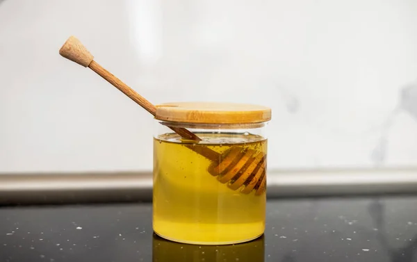 砂糖と蜂蜜入りのガラス瓶 モダンなキッチンインテリアテーブル木製のスプーン蜂蜜ロングスティック丸カバー蓋 住宅デザイン — ストック写真