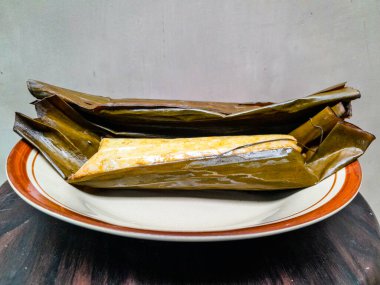 Muz yapraklarına sarılmış pirinç ruloları kahverengi seramik tabağa konur.