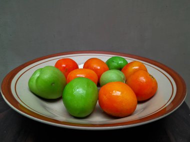 Kahverengi seramik tabakta biraz kırmızı domates ve yeşil salatalık.