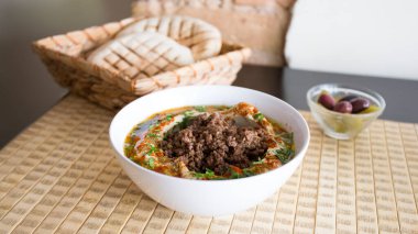 Bowl with hummus and grilled meat and vegetables on the top.