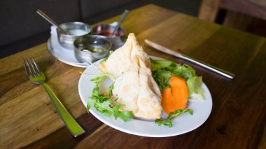 Samosa is a fried or baked dumpling with savory filling, such as seasoned potatoes, onions, peas, meat, or lentils.