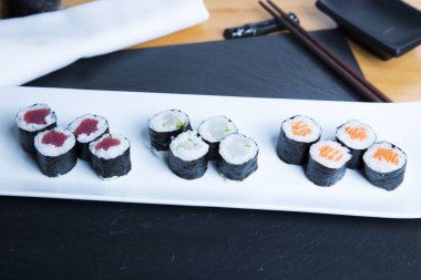 Set of sushi with variety of makis, nigiris and sashimi with fine fish like salmon and tuna.