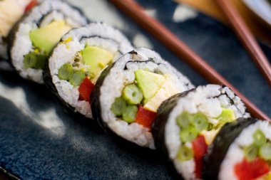 Maki sushi with rice and seaweed stuffed with vegetables and vegetarian ingredients.