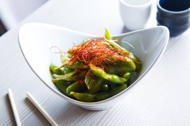 Edamame is a preparation of immature soybeans in the pod, found in cuisines with origins in East Asia. The pods are boiled or steamed and can be served with salt or other seasonings.