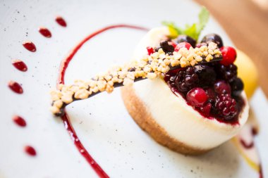 Cheesecake with red fruit sauce and fresh fruit such as raspberries, blueberries or strawberries.