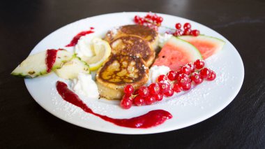 Pancakes with fresh fruit like banana, strawberries or kiwi with a dark chocolate covered.