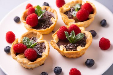 Raspberry tarts on a plate with raspberries