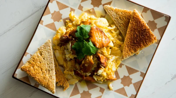Scrambled with eggs and mushrooms on toasted bread.