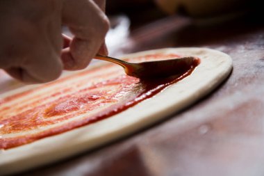 Hamuru yoğurarak pizza hazırlamak ve İtalyan ev yapımı domates sosuyla yemek pişirmek..