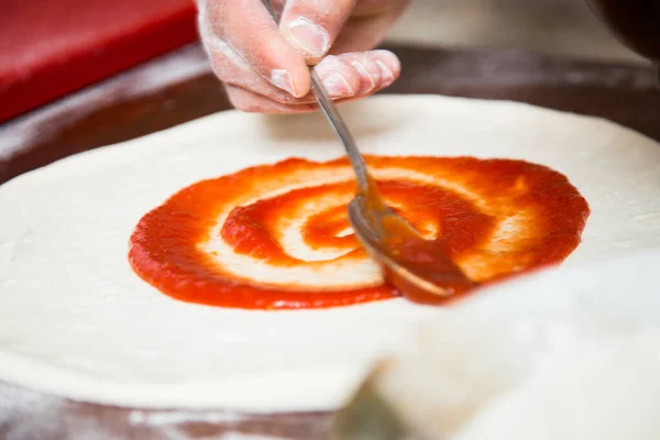 stock image Preparing a pizza by kneading the dough and cooking with Italian homemade tomato sauce.