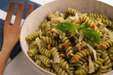 Pesto soslu makarna. Pesto, Liguria kökenli tipik bir sostur. Ana bileşeni fesleğen. Fesleğene ek olarak, çam fıstığı ve sarımsak da parmesan peyniri ve / veya koyun peyniri ve zeytinyağı ile tatlandırılmıştır..