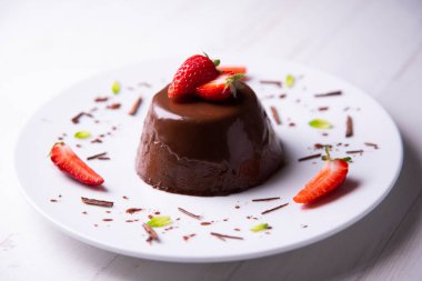 Çikolatalı Panna Cotta. Panna cotta, İtalyan Piedmont bölgesinin tipik bir tatlısıdır, süt, krema, şeker ve jölelerden yapılır ve genellikle kırmızı meyve reçelleri ile süslenir..